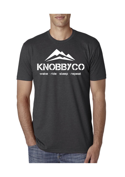 Charcoal KnobbyCo brand mountain bike t-shirt with mountains and tag line. Wake. Ride. Sleep. Repeat.